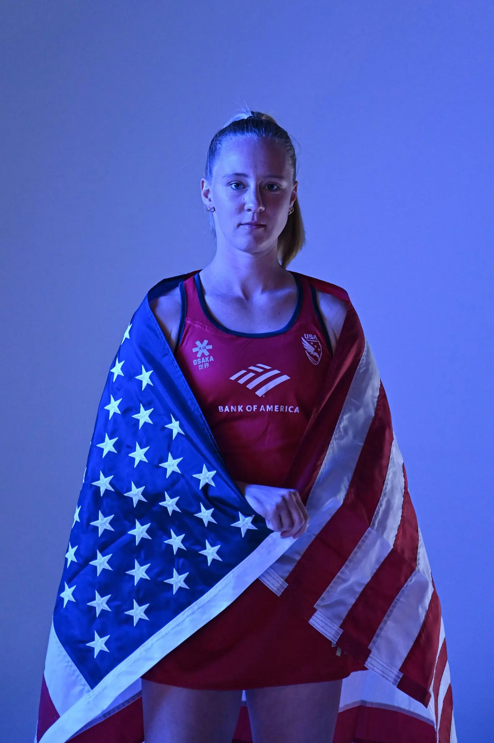 Leah Crouse poses wrapped in an American flag against a blue backdrop.