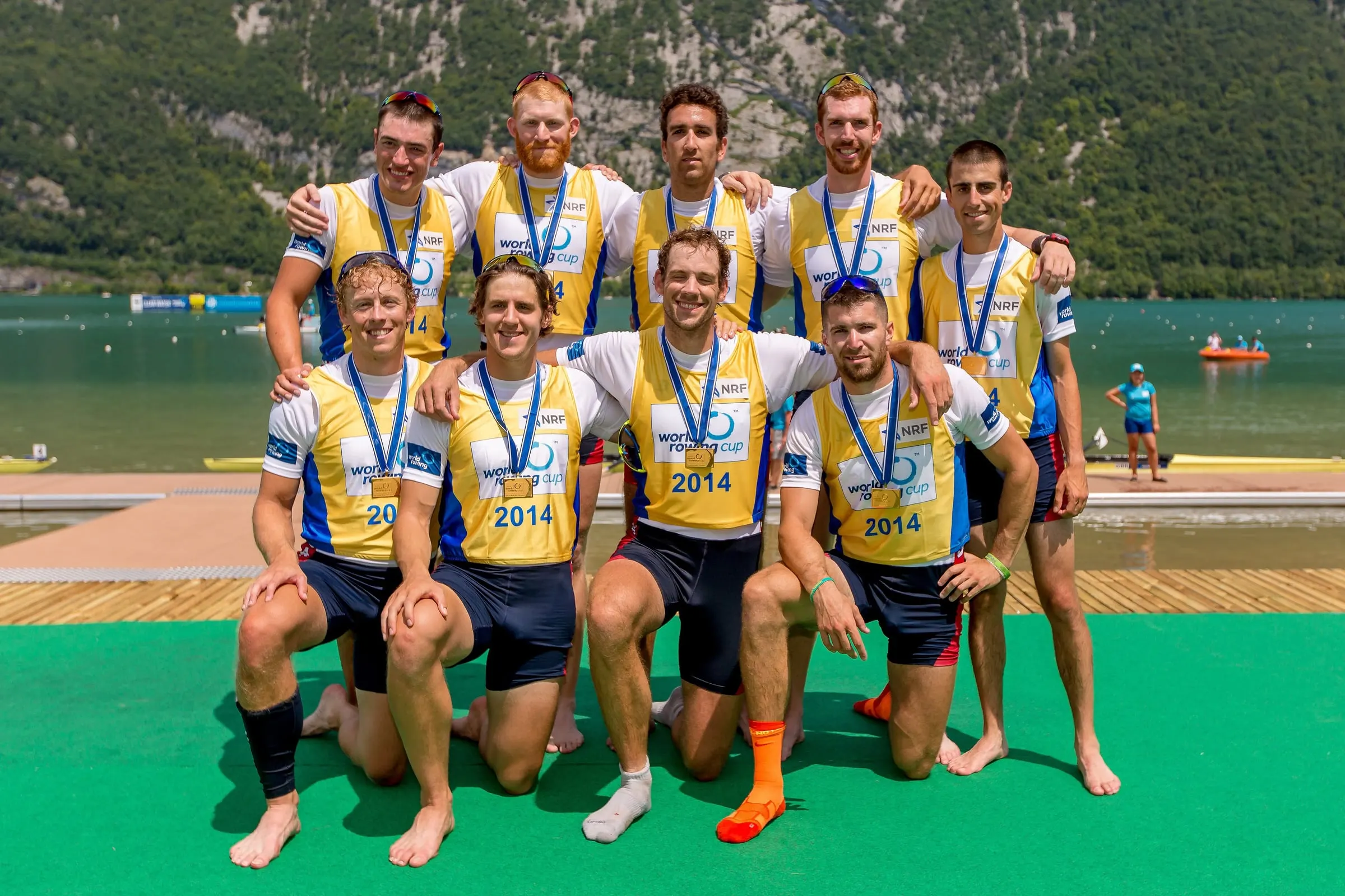 A U.S. men's rowing crew poses with medals on a dock at a 2014 regatta.