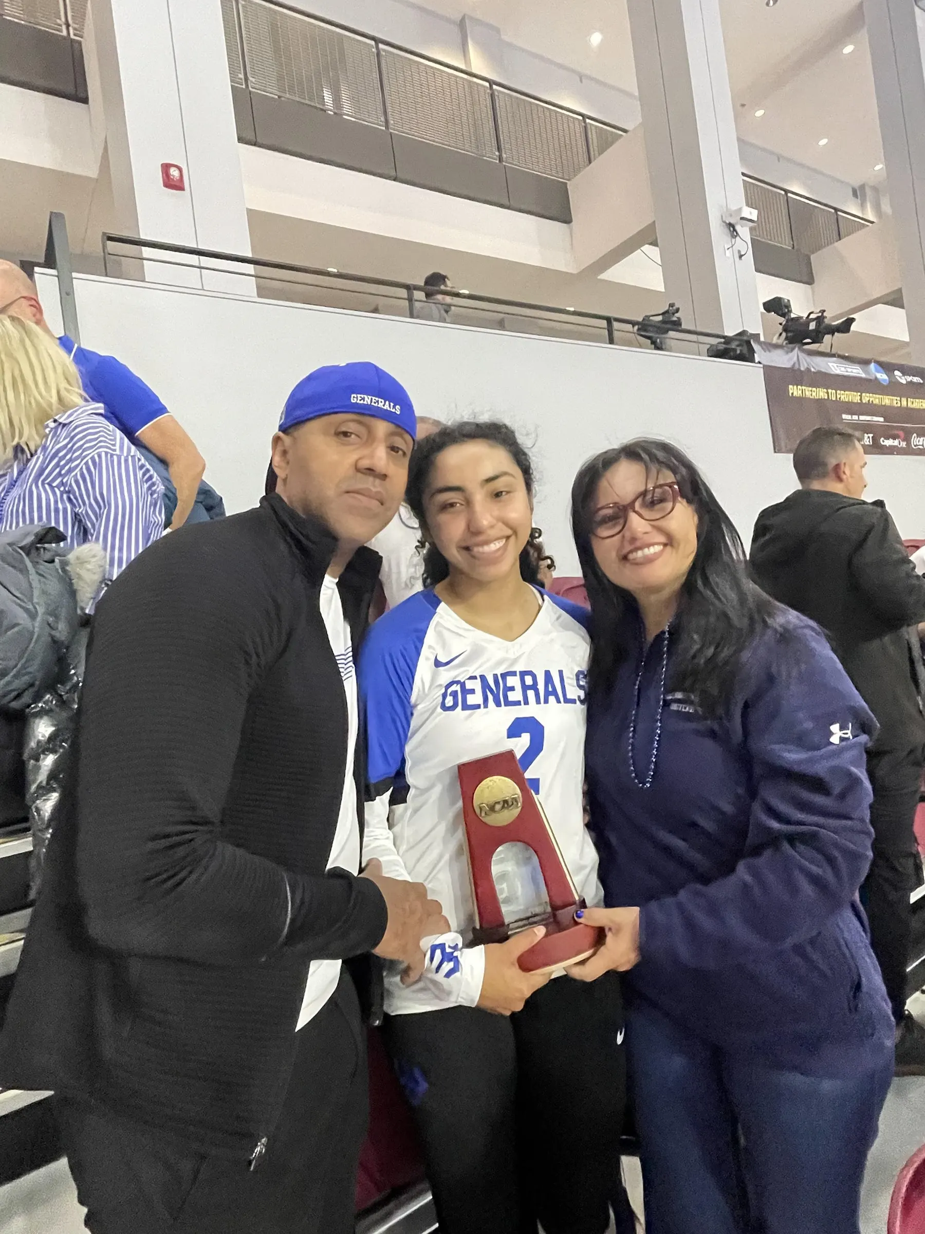 Ramon, Viviana and Nelva Vasquez hold a trophy in an arena.